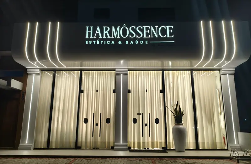 Fachada da Harmôssence à noite, com o letreiro iluminado