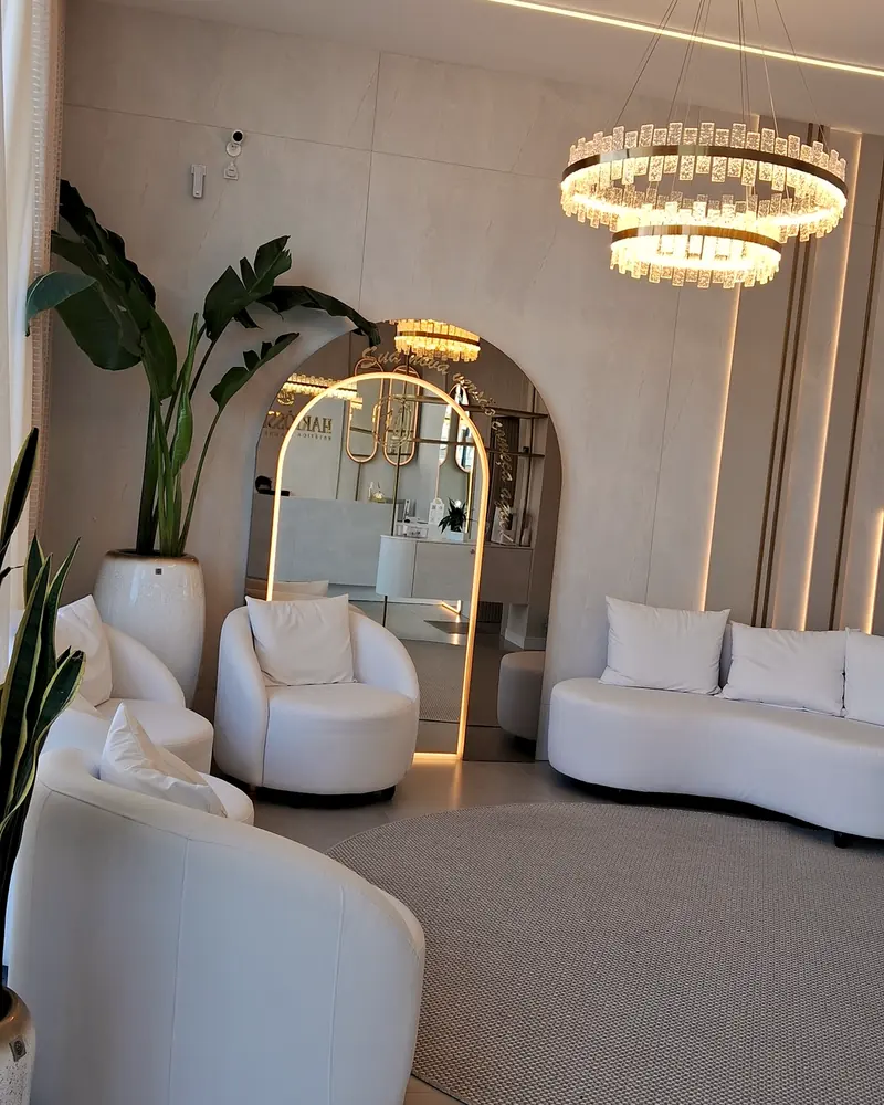 Recepção da Harmôssence com arcos iluminados, lustre e poltronas brancas